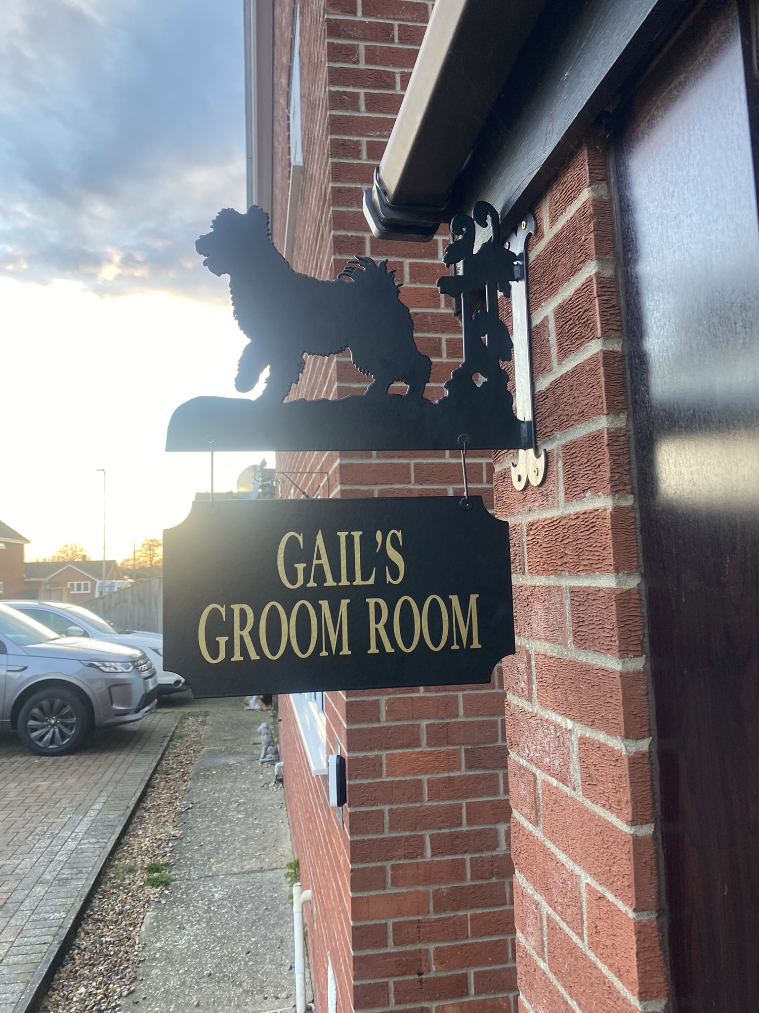 The Gail’s Groom Room sign on a red brick wall, with a black dog silhouette bracket